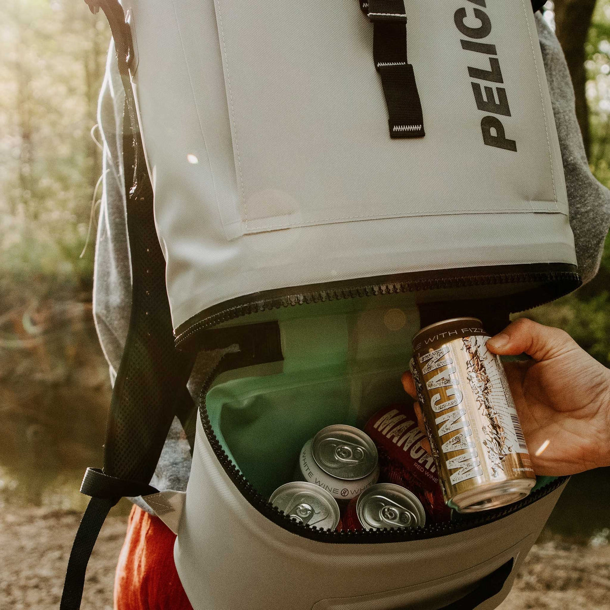 Pelican™ Dayventure Backpack Soft Cooler canned beverages being pulled out of the cooler compartment