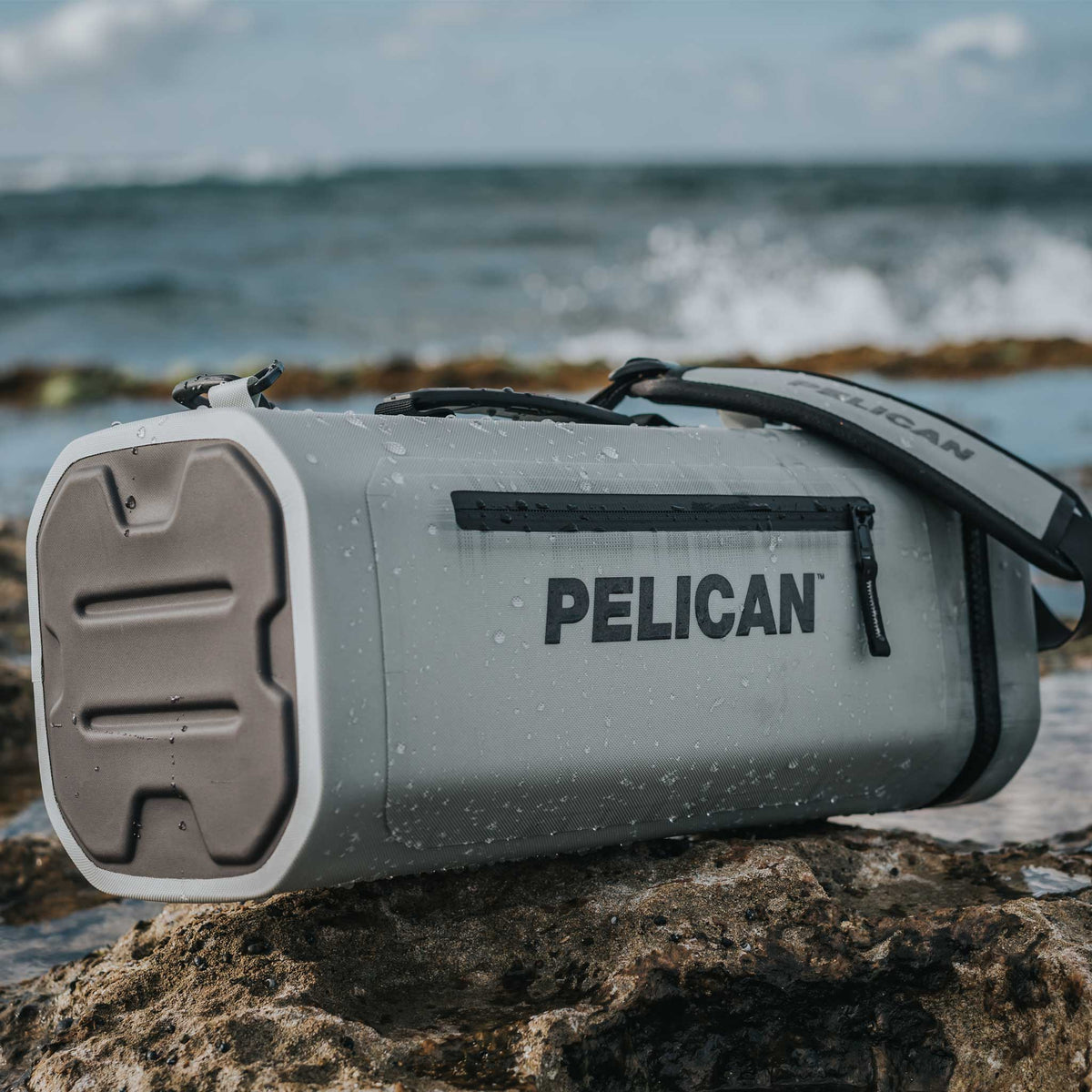Pelican™ Dayventure Sling Soft Cooler on the beach splashed with water